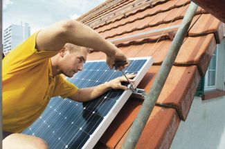 Mitarbeiter montiert auf dem Dach Fotovoltaikanlage  