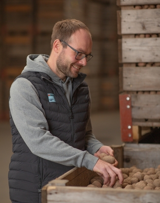 Junger Mann vor einer Palette mit Kartoffeln